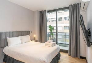 ブエノスアイレスにあるLive Soho Boutique Apartments Arcosのベッドと大きな窓のある寝室