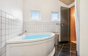 Una bañera blanca en un baño con azulejos blancos. en Nice Home In Glesborg With Sauna, en Glesborg