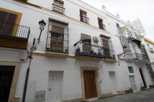 ein weißes Gebäude mit Fenstern und Balkonen auf einer Straße in der Unterkunft Apartamentos Centro Puerto de Santa Maria in El Puerto de Santa María