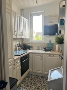 a kitchen with white cabinets and a sink and a window at Maison Cosy Bord de Mer in Dives-sur-Mer +9 photos