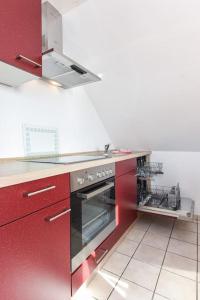 a kitchen with red cabinets and a stove top oven at Bensersiel Ferienwohnung Smutje mit Balkon in Bensersiel