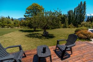a deck with three chairs and a cat sitting on it at Cabaña Mauka in El Bolsón +32 photos