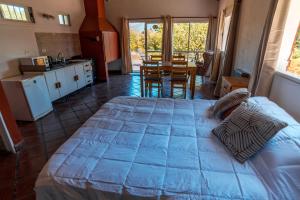 a bedroom with a bed and a kitchen with a table at Cabaña Mauka in El Bolsón
