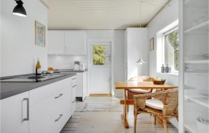 a kitchen with white cabinets and a wooden table at 2 Bedroom Beautiful Home In Gilleleje in Gilleleje
