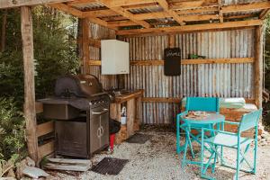 a outdoor kitchen with a grill and a table and chairs at Golden Bay Glamping in Takaka