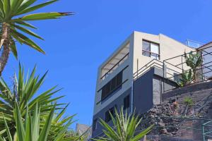 ein Gebäude mit Palmen davor in der Unterkunft Yellow House in Jardim do Mar