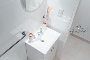 a white bathroom with a sink and a mirror at EmBruHadas Yellow in San Salvador de Jujuy