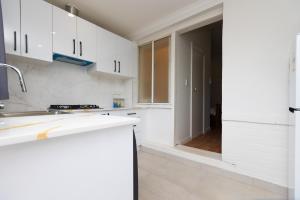a white kitchen with white cabinets and a sink at Glenelg North Modern Studio, QBed,Wifi, Pet in Glenelg +5 photos