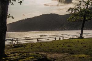 eine Gruppe von Menschen, die am Strand in der Nähe des Wassers stehen in der Unterkunft Consulado Praia Hotel in Guarujá