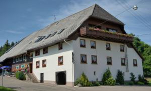 ein großes weißes Gebäude mit einem Gamer-Dach in der Unterkunft Gasthaus Pension Zum Löwen in Grafenhausen