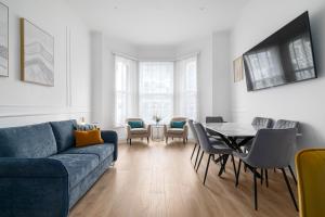 a living room with a blue couch and a table and chairs at Luxury 2 bed Flat in Notting Hill in London