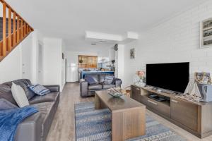 a living room with a couch and a flat screen tv at Unit 5 13 Short Street, Merimbula in Merimbula