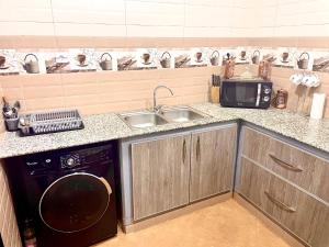 a kitchen with a sink and a washing machine at Résidence Inaya 2 SANS GARAGE Accès réservé aux voyageurs déclarés Uniquement PAS DE VISITEURS in Oran