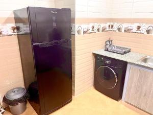 a black refrigerator in a kitchen with a washing machine at Résidence Inaya 2 SANS GARAGE Accès réservé aux voyageurs déclarés Uniquement PAS DE VISITEURS in Oran