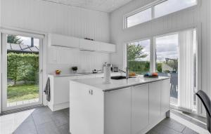 una cucina bianca con armadi bianchi e finestre di Holiday Home Johs Jensensvej a Egeskov