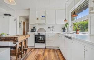 a white kitchen with white cabinets and a wooden floor at Pet Friendly Home In Allinge With Wifi in Allinge