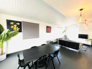 a dining room with a black table and chairs at Penthouse Happiness in Papeete