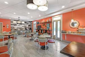a restaurant with orange walls and tables and chairs at Best Western Plus St. Simons in Saint Simons Island