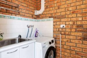 a kitchen with a washing machine and a brick wall at House on the Hillside with City Views Sleeps 12 in Howrah