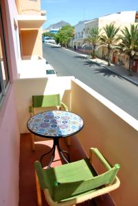 a table and chairs on a balcony with a street at Tambarina Guest House in Mindelo