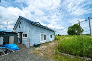 a small blue house in a field with a sky at The Jardin in Kami-furano