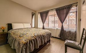 a bedroom with a bed and two large windows at Departamento en centro de Cuenca in Cuenca