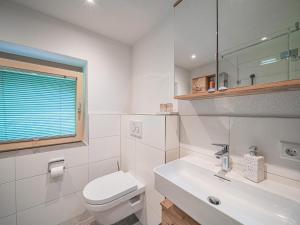 a white bathroom with a toilet and a sink at Gastl in Hopfgarten im Brixental +14 photos