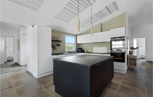 a kitchen with white cabinets and a black island at Awesome Home In Hvide Sande With Sauna in Bjerregård