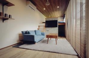 ein Wohnzimmer mit einer blauen Couch und einem Tisch in der Unterkunft Shikochu Base - Vacation STAY 76591v in Shikokuchuo