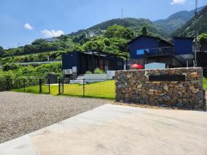 ein Haus mit einer Steinmauer neben einem Berg in der Unterkunft Shikochu Base - Vacation STAY 76591v in Shikokuchuo