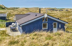 a blue house sitting on top of a field at Holiday Home Baunebjergvej Hvide Sande in Havrvig