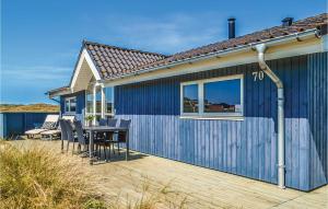 a blue house with a table and chairs on a deck at Holiday Home Baunebjergvej Hvide Sande in Havrvig