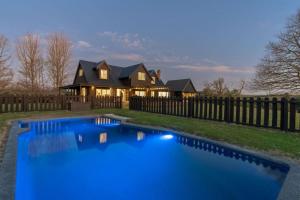 a house with a blue pool in front of a fence at Hawthorn Cottage - Deluxe Private Guesthouse in Tamahere