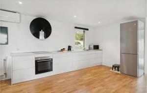 a kitchen with white cabinets and a black appliance at 2 Bedroom Nice Home In Jægerspris in Jægerspris