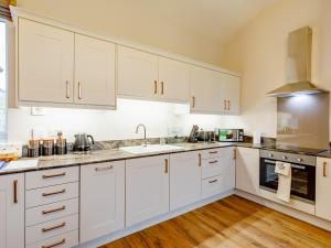 une cuisine avec des armoires blanches et un évier dans l'établissement Merry Burn Barn - Uk3325, à Falstone