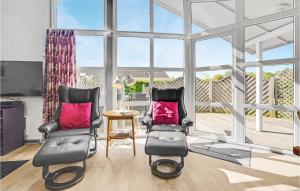 two chairs and a table in a living room with windows at Holiday Home Rævebæk Sydals V Denmark in Skovby
