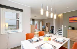 a dining room with a white table and orange chairs at Unendliche See in Olpenitz