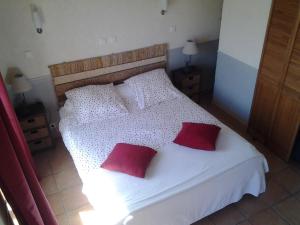 a bedroom with a white bed with two red pillows at Domaine de Collen in Lépine