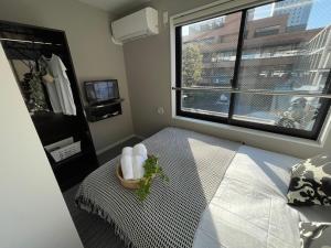 a bedroom with a bed with a window and a basket of towels at COMMA HOUSE Shinjuku 303 in Tokyo