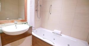 a white bathroom with a sink and a bath tub at Harbour Heights Hotel in Poole