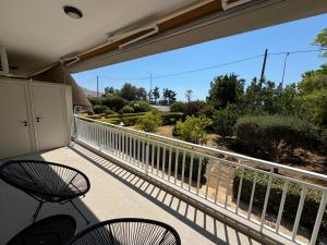 een balkon met 2 stoelen en uitzicht op een tuin bij Resort Beach Living in Lagonisi in Kalívia Thorikoú