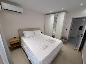 een slaapkamer met een wit bed met handdoeken erop bij Resort Beach Living in Lagonisi in Kalívia Thorikoú