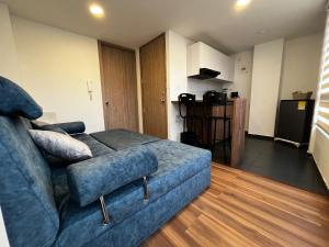 a living room with a blue couch and a kitchen at Apartamento de una habitación in Pasto