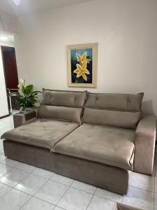 a brown couch in a living room with a painting at Apartamento em Cabo Frio in Cabo Frio