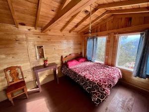 a bedroom in a log cabin with a bed and a table at Cabaña sheymar in San Mateo Río Hondo