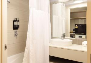 a bathroom with a white shower curtain and a sink at Sudima Auckland Airport in Auckland