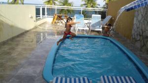 a young girl jumping into a swimming pool at Pousada Costa Coral in Tamandaré