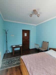 a bedroom with blue walls and a bed and a chair at Altyn Bulak Guest hause in Karakol +7 photos