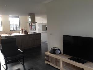 a living room with a flat screen tv and a chair at Suite School 15 A in Zonnemaire