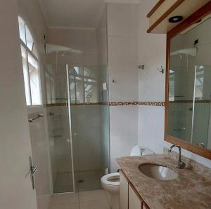 a bathroom with a shower and a toilet and a sink at Casa temporada com piscina in Caraguatatuba +6 photos